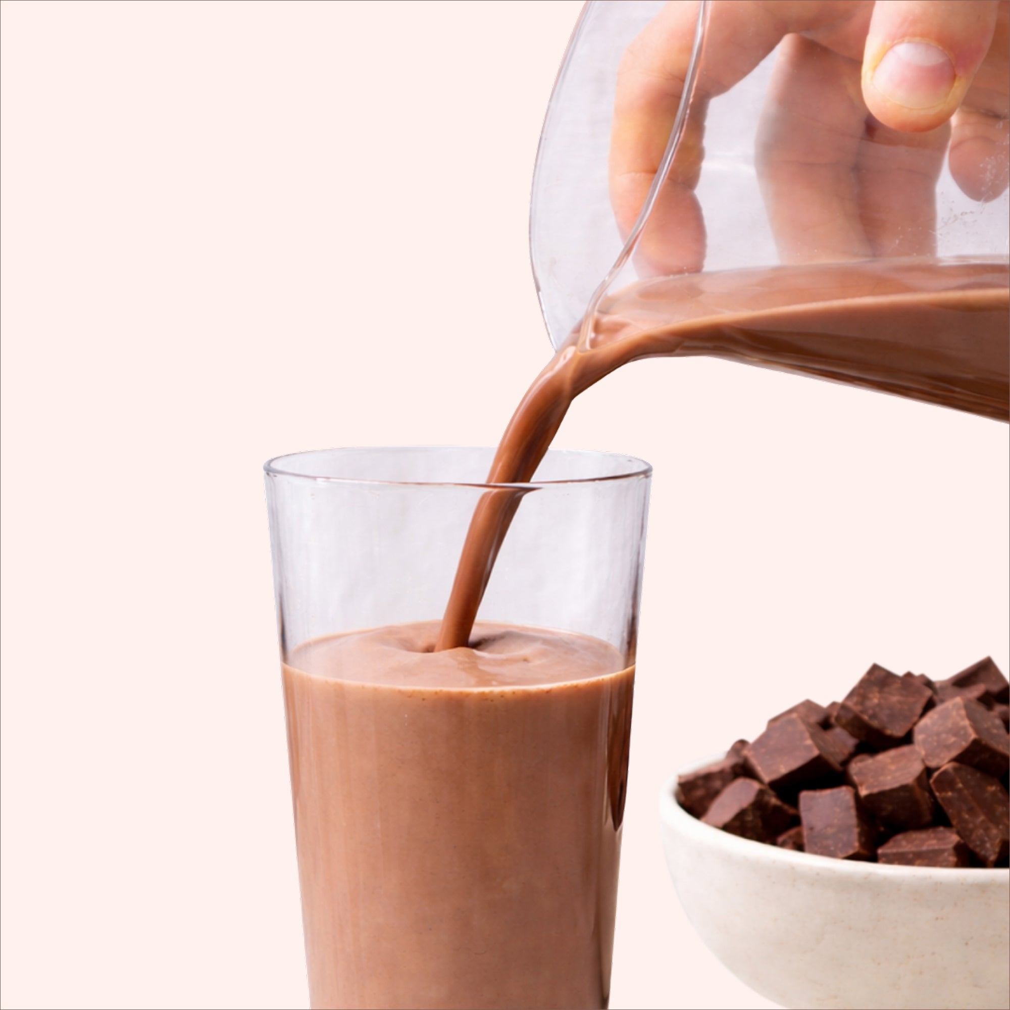40738242232369 Chocolate milk being poured into a glass with chocolate pieces on a white background