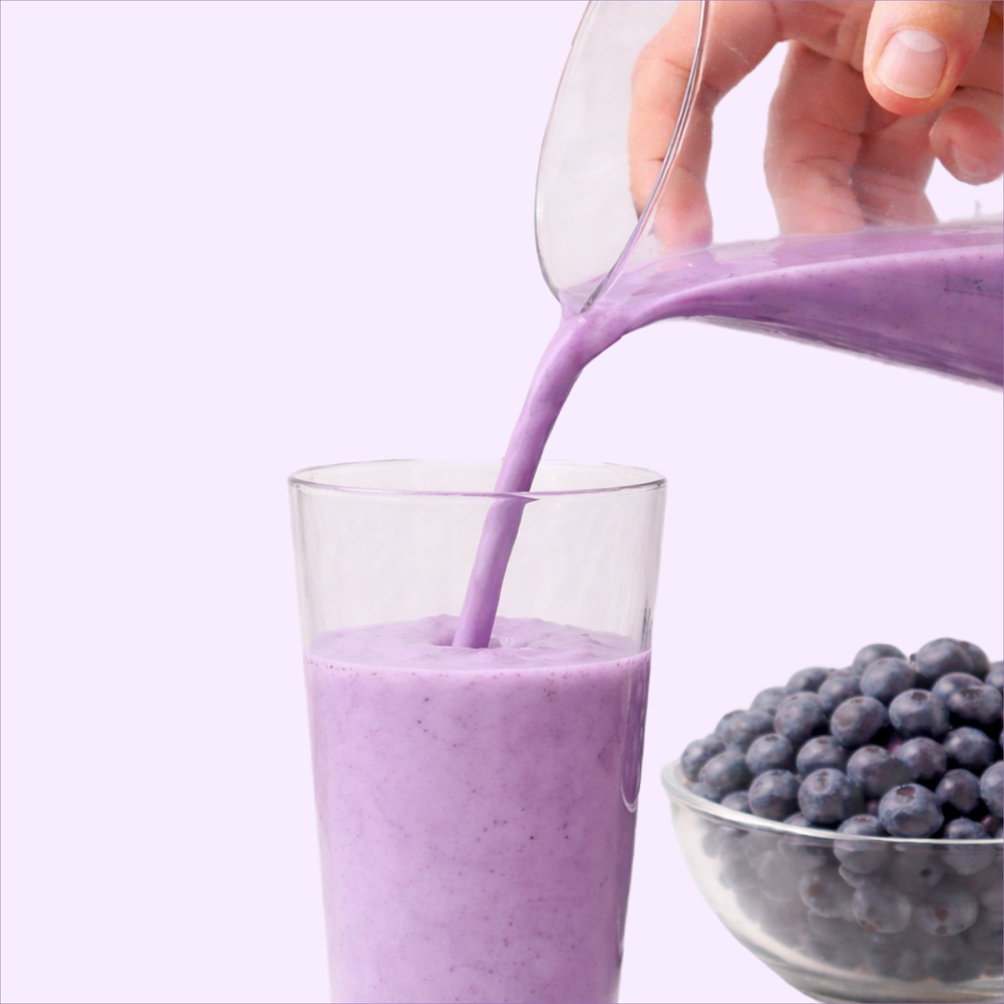 40793201082417 Purple smoothie being poured into a glass with blueberries on a white background