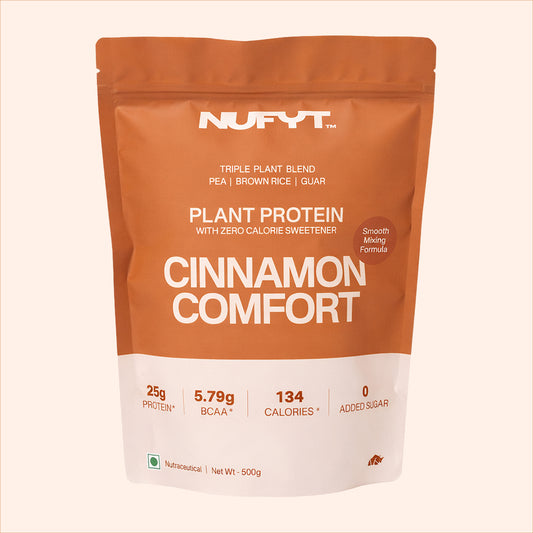 40738732539953 Nufyt Cinnamon Comfort plant protein package with a glass of protein shake, scoop, and cinnamon sticks on a beige background